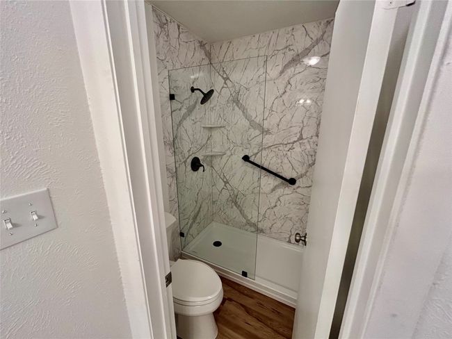 Full bath with a marble finish shower, toilet, and wood finished floors | Image 18