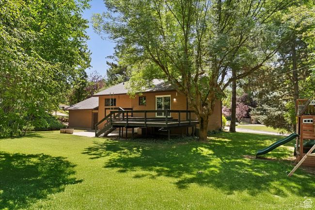 View of grassy yard with a playground, a deck, and stairs | Image 42