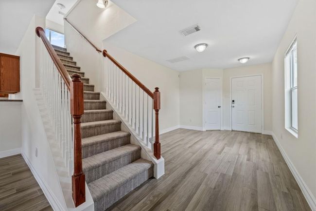 Open staircase with wood railing leading to upstairs bedrooms. | Image 6