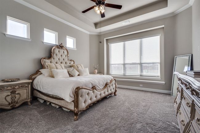 Bedroom featuring ceiling fan, light colored carpet, ornamental molding, and a raised ceiling | Image 16