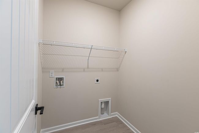 Clothes washing area featuring wood finished floors, baseboards, hookup for an electric dryer, hookup for a washing machine, and laundry area | Image 11