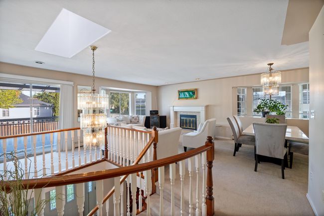 Living area with a healthy amount of sunlight, a notable chandelier, and carpet flooring | Image 8
