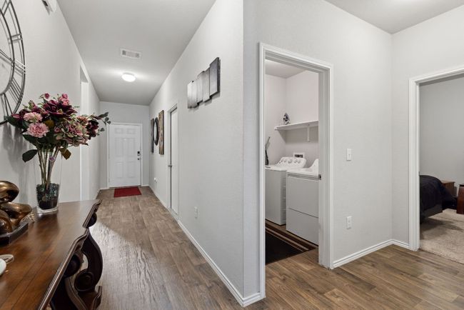 Hall featuring separate washer and dryer, wood-vinyl finished floors, and baseboards | Image 16