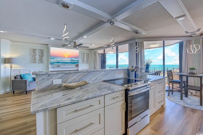 Kitchen featuring tasteful backsplash, hanging light fixtures, white cabinetry, stainless steel range with electric stovetop, and light wood-type flooring | Image 10