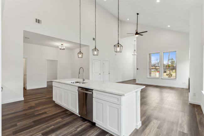 Kitchen with stainless steel dishwasher, open floor plan, high vaulted ceiling, a center island with sink, and white cabinetry | Image 18