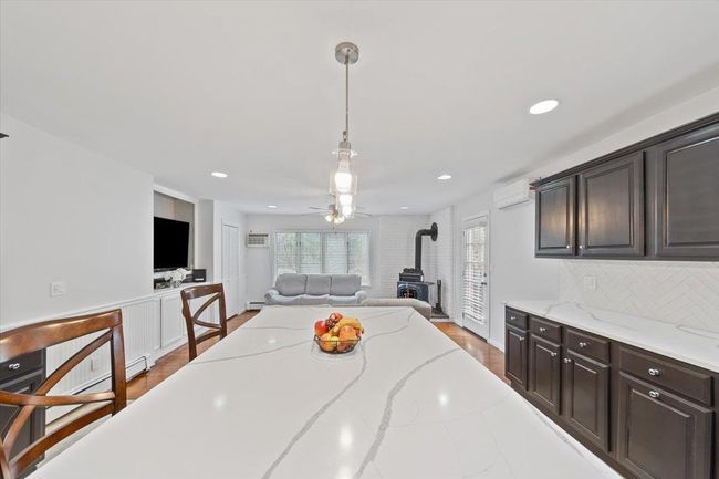 Dining room with wood finished floors, a wood stove, an AC wall unit, ceiling fan, and recessed lighting | Image 33