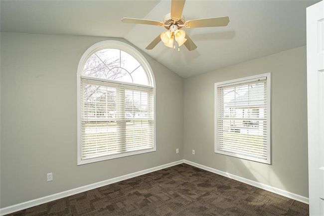 Spare room featuring baseboards, a healthy amount of sunlight, ceiling fan, and vaulted ceiling | Image 23