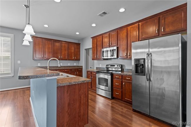 Kitchen with appliances with stainless steel finishes, dark wood-style floors, recessed lighting, and hanging light fixtures | Image 4