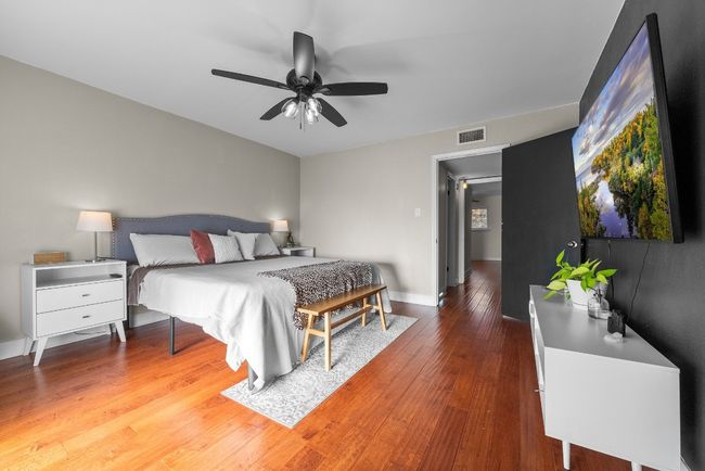 Primary bedroom featuring ceiling fan, wood-style flooring, a spacious walk-in closet and access to the balcony with a view to the pool | Image 26