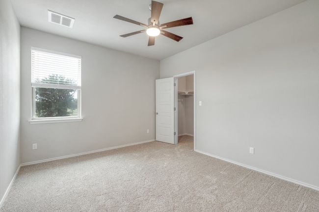 Unfurnished bedroom with light colored carpet, a spacious closet, ceiling fan, and a closet | Image 26