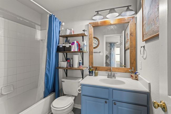Bathroom featuring a textured wall, shower / tub combo, toilet, and vanity | Image 17
