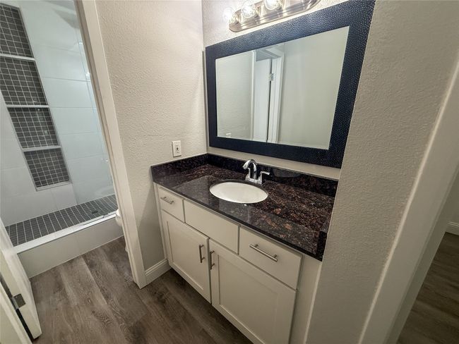 Bathroom with wood finished floors, a textured wall, vanity, and a shower stall | Image 26