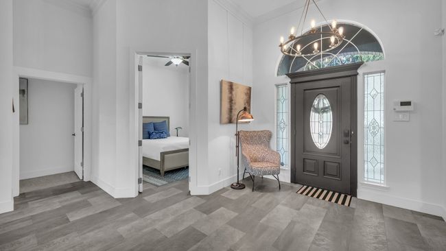 Entrance foyer with a towering ceiling, a chandelier, plenty of natural light, crown molding, and wood finished floors | Image 4