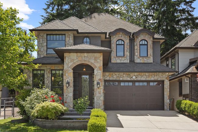 French provincial home featuring stone siding, driveway, and an attached garage | Image 33