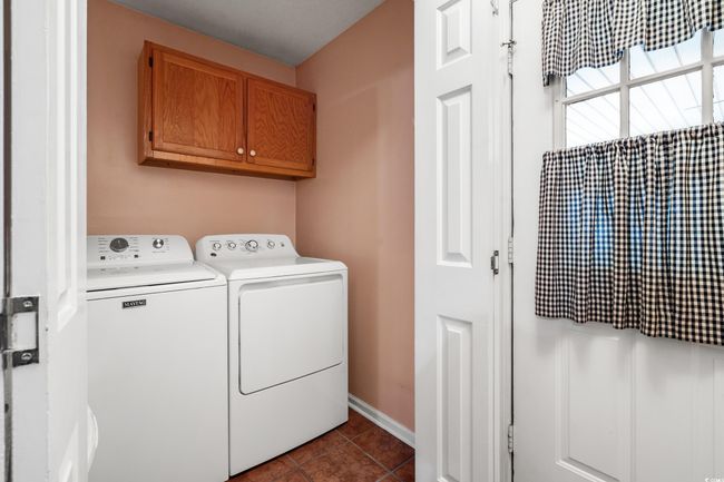 Laundry room featuring washing machine and dryer, cabinet space, dark tile patterned floors, and baseboards | Image 19