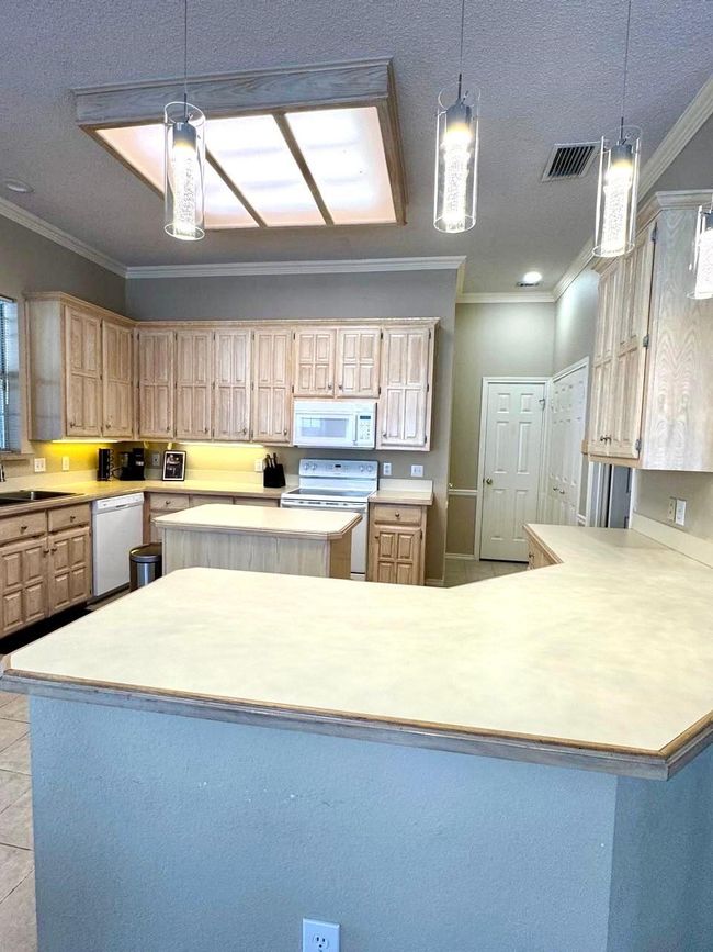 Kitchen featuring white appliances, visible vents, light countertops, and a kitchen island | Image 8