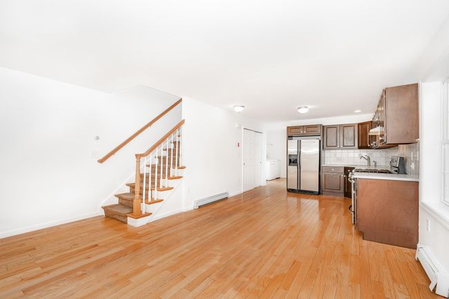 Kitchen featuring decorative backsplash, light countertops, baseboard heating, appliances with stainless steel finishes, and a baseboard heating unit | Image 12