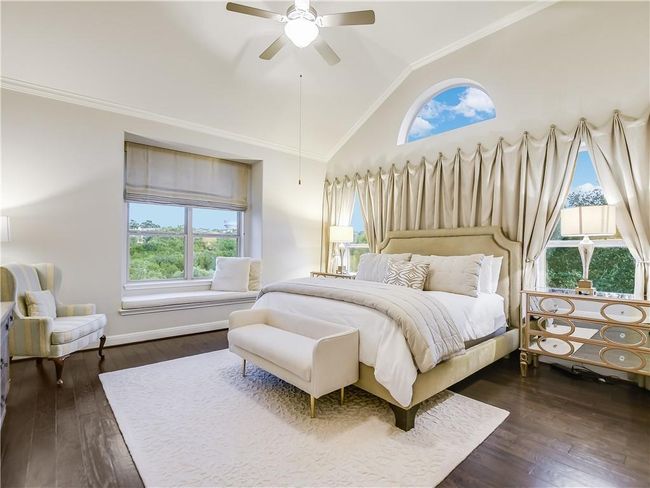 Bedroom with multiple windows, wood-type flooring, crown molding, a ceiling fan, and high vaulted ceiling | Image 22