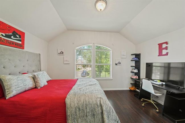 Vaulted ceilings and a large arched window fill this guest retreat with natural light, offering a serene space with warm wood-style flooring and fresh neutral finishes. | Image 37