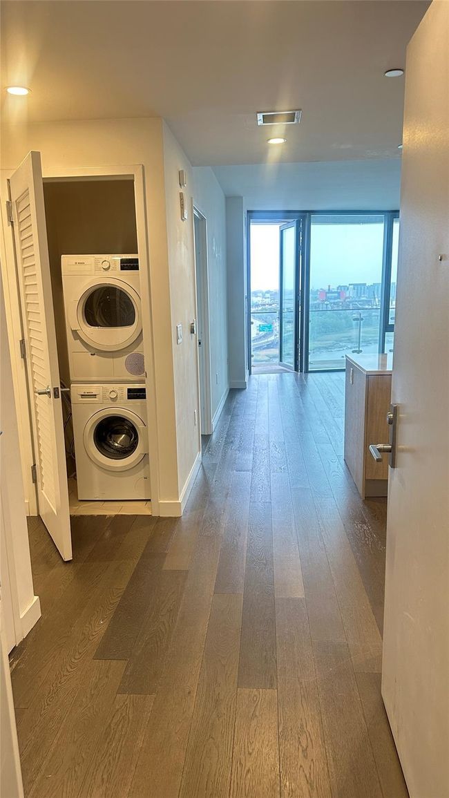 Hallway with stacked washer and clothes dryer and dark wood-type flooring | Image 10