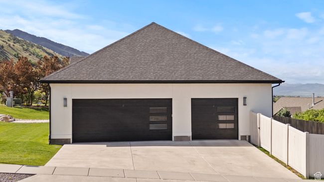 View of side of home featuring a mountain view, roof with shingles, a garage, and stucco siding | Image 43