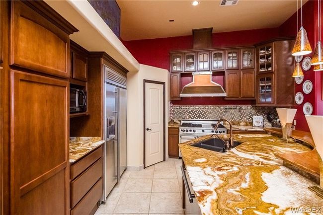 Kitchen with custom range hood, high end appliances, decorative backsplash, and glass insert cabinets | Image 39