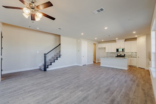 Unfurnished living room featuring a ceiling fan, stairs, light wood-type flooring, and recessed lighting | Image 9