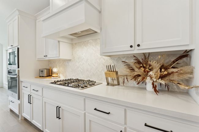 Kitchen with stainless steel appliances, premium range hood, decorative backsplash, light countertops, and white cabinets | Image 11