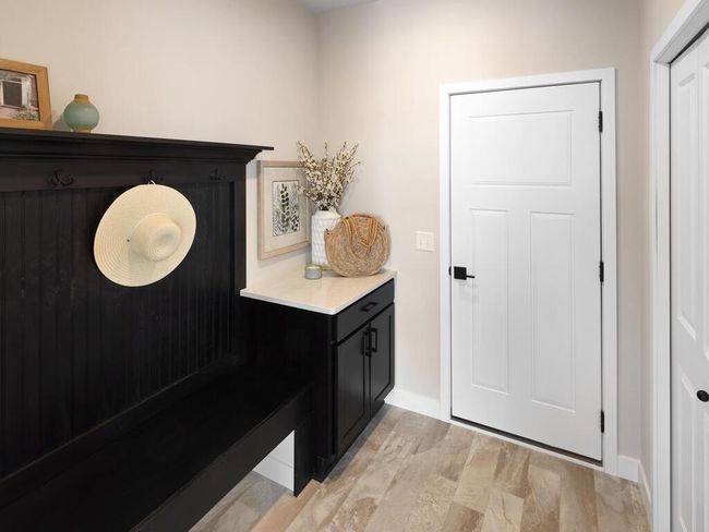 A mudroom featuring a custom boot bench for seating and storage, a dedicated drop zone for organizing devices and keys, and a coat closet for hanging outerwear. | Image 17