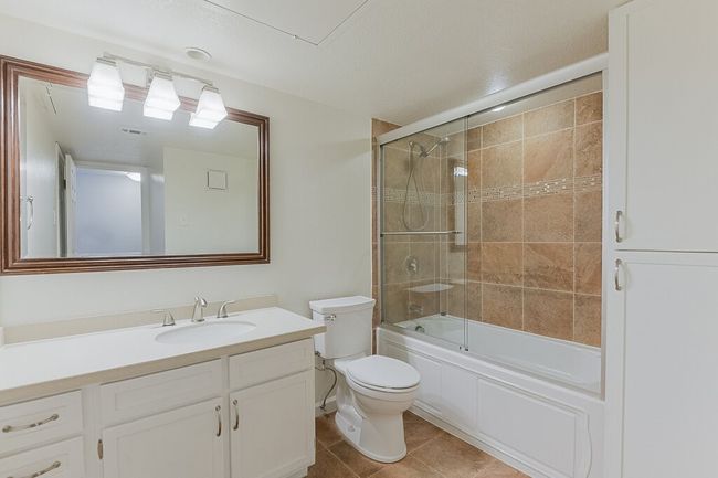Full bathroom with vanity, visible vents, toilet, combined bath / shower with glass door, and tile patterned floors | Image 20