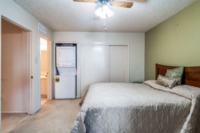 Bedroom featuring stacked washer and clothes dryer, a textured ceiling, light carpet, a closet, and a ceiling fan | Image 17