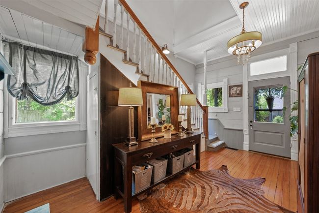 Foyer entrance featuring hardwood / wood-style floors, stairs, a chandelier, and a wooden ceiling with exposed beams | Image 7