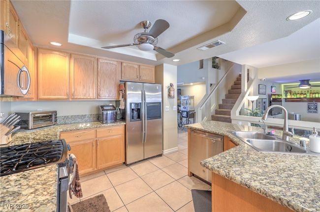 Kitchen with appliances with stainless steel finishes, light tile patterned floors, a tray ceiling, a ceiling fan, and recessed lighting | Image 29