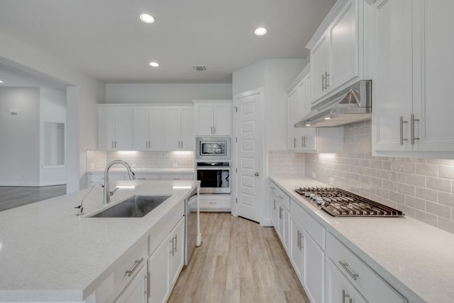Kitchen with backsplash, white cabinets, stainless steel appliances, light wood-type flooring, and recessed lighting | Image 11