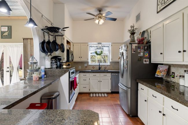 Kitchen featuring stainless steel appliances, a ceiling fan, a sink, white cabinetry, and tasteful backsplash | Image 19
