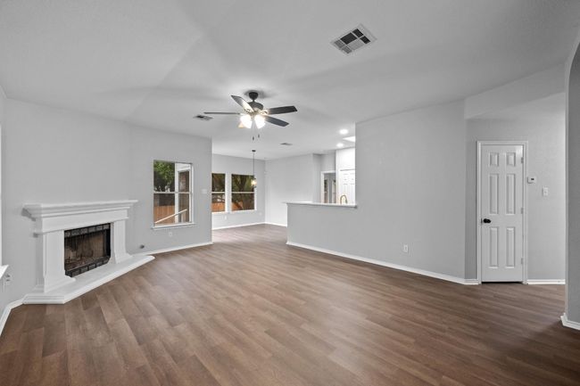 living room featuring a ceiling fan, a fireplace with raised hearth, and new flooring | Image 6