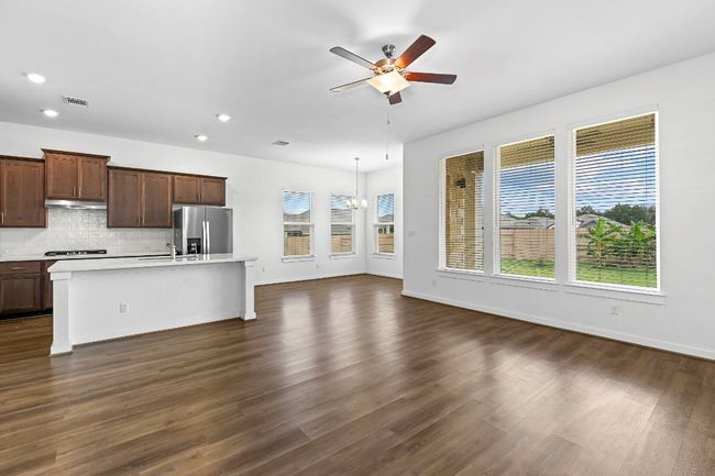 Kitchen featuring stainless steel fridge, a ceiling fan, light countertops, a kitchen island with sink, and decorative backsplash | Image 18