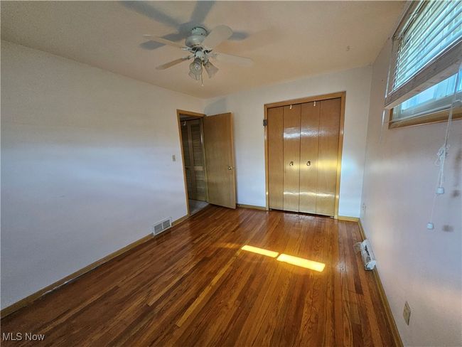 Unfurnished bedroom with baseboards, visible vents, a ceiling fan, wood finished floors, and a closet | Image 7