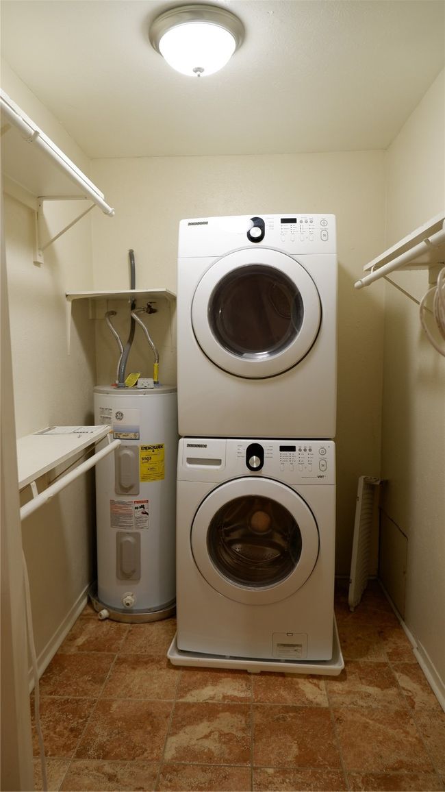 Washroom featuring stacked washer / dryer and water heater | Image 12