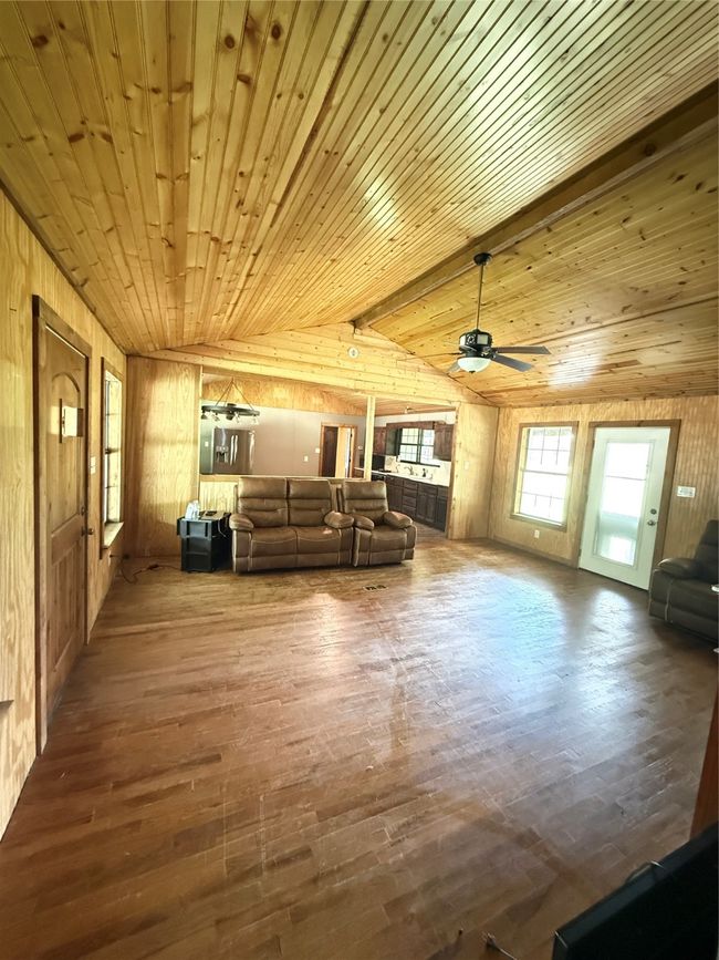 Living area with wood walls, a ceiling fan, wood finished floors, and wooden ceiling | Image 16