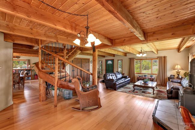 Living room with a chandelier, plenty of natural light, light wood-style floors, and a wood ceiling with exposed beams | Image 11