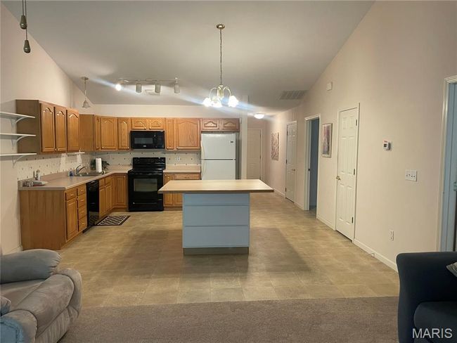 Kitchen featuring black appliances, vaulted ceiling, a sink, open floor plan, and light countertops | Image 9