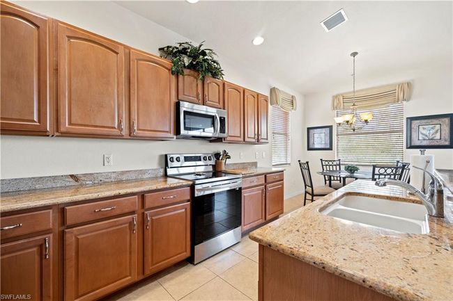 Kitchen with visible vents, a sink, appliances with stainless steel finishes, a notable chandelier, and decorative light fixtures | Image 15