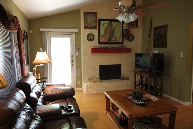 Living area featuring ceiling fan, wood finished floors, vaulted ceiling, and a fireplace | Image 9