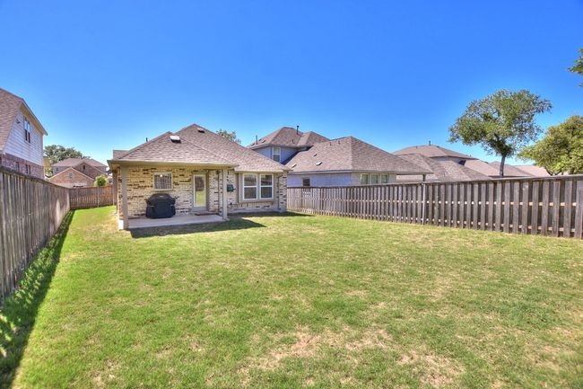 Back of property with a shingled roof, a patio area, a lawn, a fenced backyard, and brick siding | Image 28