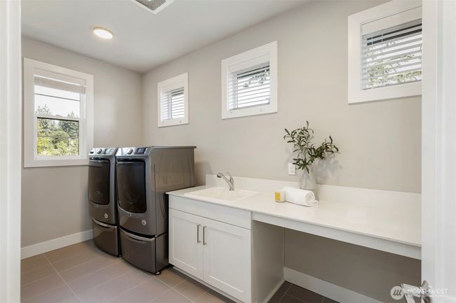 This upstairs laundry room is bright, spacious, and thoughtfully designed with a deep utility sink, extended folding counter, and built-in cabinetry for storage. Please note: the washer and dryer are not included in the sale. | Image 36