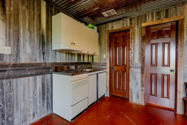 Kitchen with white cabinets, white gas range, visible vents, finished concrete floors, and custom range hood | Image 22