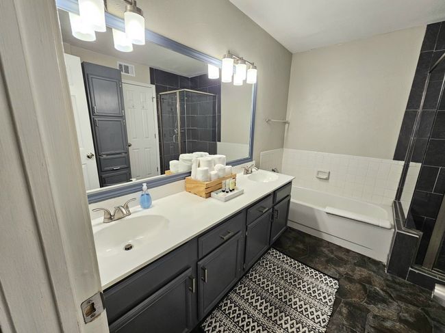 Bathroom with a stall shower, a bath, double vanity, and stone finish floors | Image 9