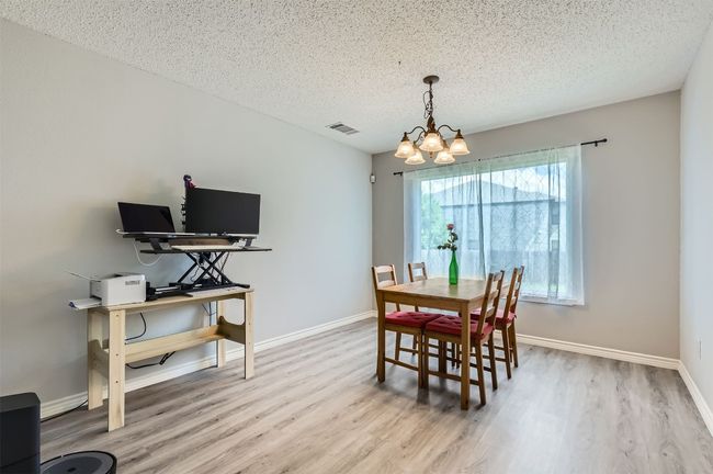 Dining space with a chandelier, wood finished floors, baseboards, and a textured ceiling | Image 8