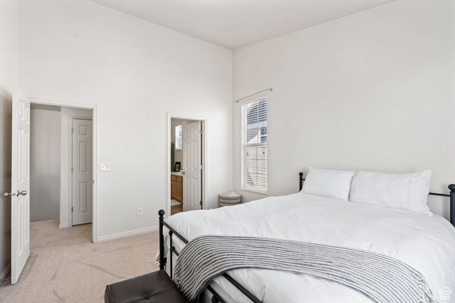 Bedroom with baseboards, connected bathroom, a high ceiling, and light carpet | Image 9